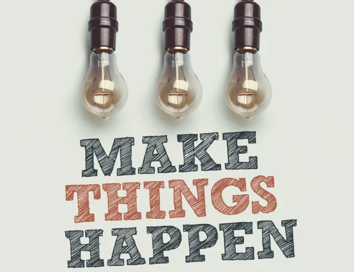 Trzy wiszące żarówki na jasnym tle nad napisem „MAKE THINGS HAPPEN”